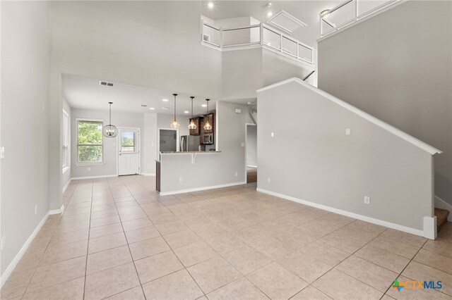 1904 Garretts Way, Manchaca, TX 78652 - unfurnished living room featuring a high ceiling, baseboards, stairs, and light tile patterned floors