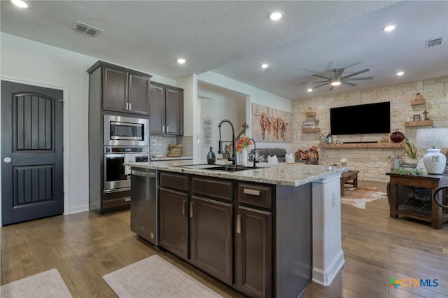 1531 Esser Xing, Canyon Lake, TX 78132 - kitchen featuring stainless steel appliances, a ceiling fan, light stone countertops, dark wood finished floors, and a textured ceiling