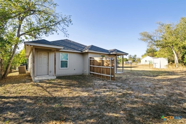 back of house featuring a storage shed and central air condition unit