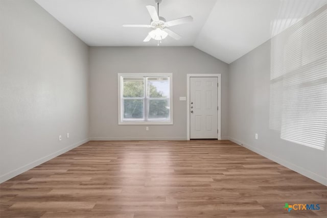 empty room with ceiling fan, light hardwood / wood-style flooring, and vaulted ceiling