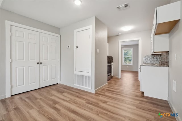 kitchen with backsplash, sink, light hardwood / wood-style floors, and white cabinets