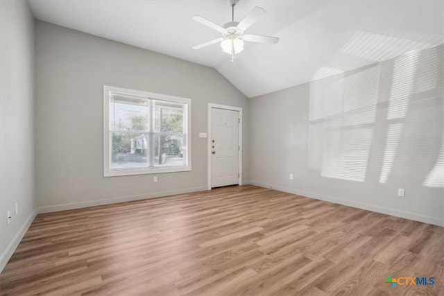 empty room featuring ceiling fan, light wood-type flooring, and vaulted ceiling