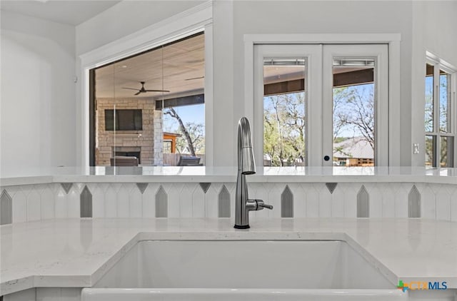12 Lago Viento Ln, Belton, TX 76513 - room details with light stone countertops, a stone fireplace, ceiling fan, a sink, and backsplash