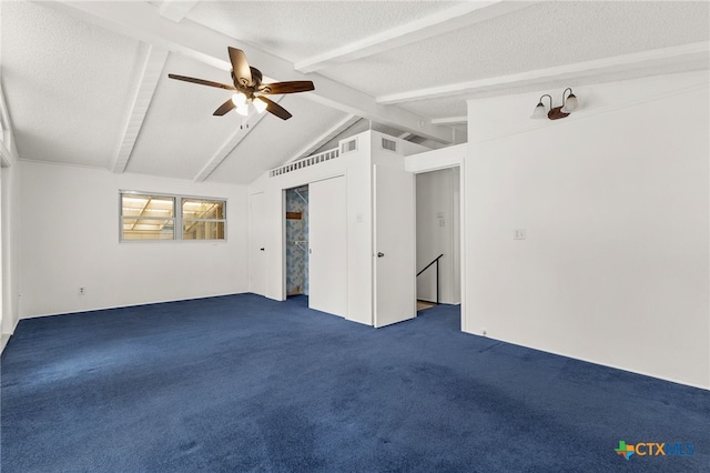 spare room featuring lofted ceiling with beams, ceiling fan, dark carpet, and a textured ceiling