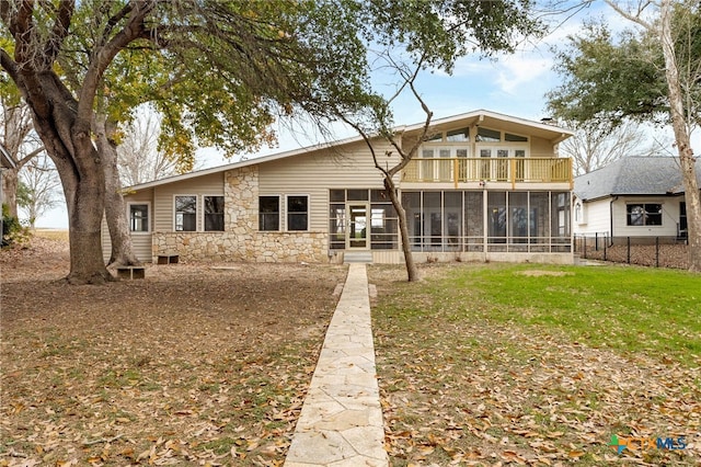 rear view of property with a yard, a sunroom, and a balcony