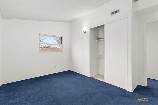 unfurnished bedroom with carpet, lofted ceiling, a textured ceiling, and a closet