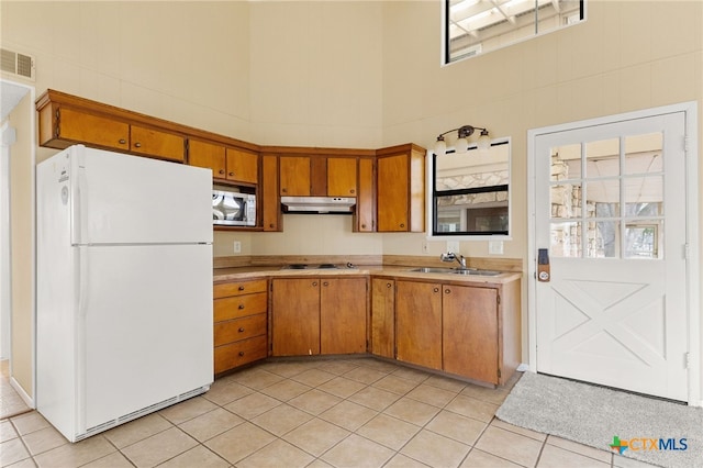 kitchen featuring a high ceiling, sink, light tile patterned floors, and white appliances