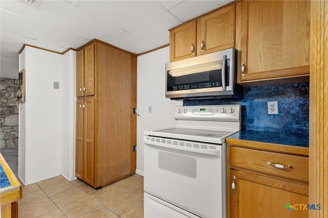 kitchen with tasteful backsplash, light tile patterned floors, and electric stove