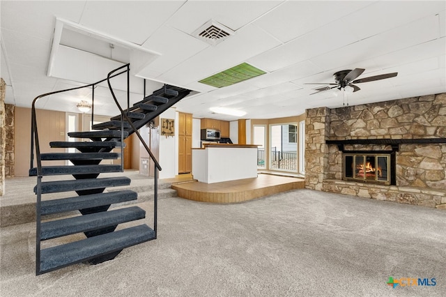 unfurnished living room featuring ceiling fan, a fireplace, and carpet floors