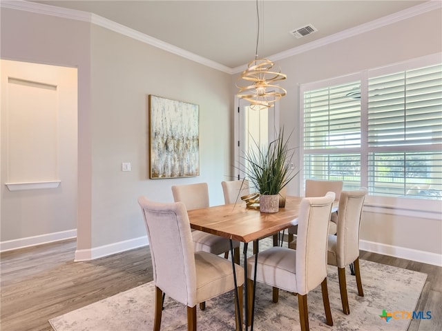 dining space with hardwood / wood-style flooring, ornamental molding, and a chandelier