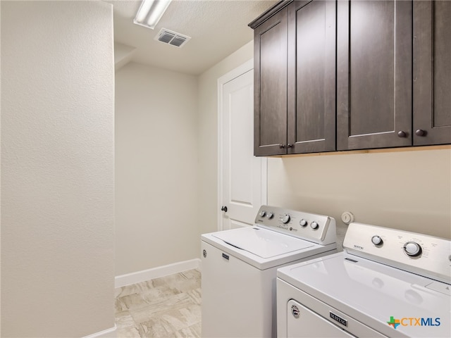 clothes washing area featuring cabinets, washing machine and dryer, and a textured ceiling