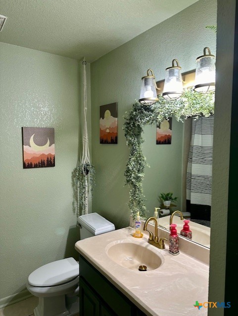 bathroom featuring vanity, a textured ceiling, and toilet