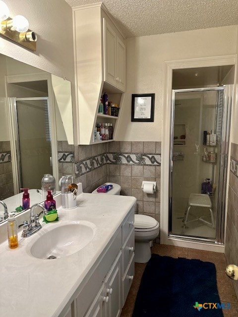 bathroom with tile walls, an enclosed shower, and a textured ceiling