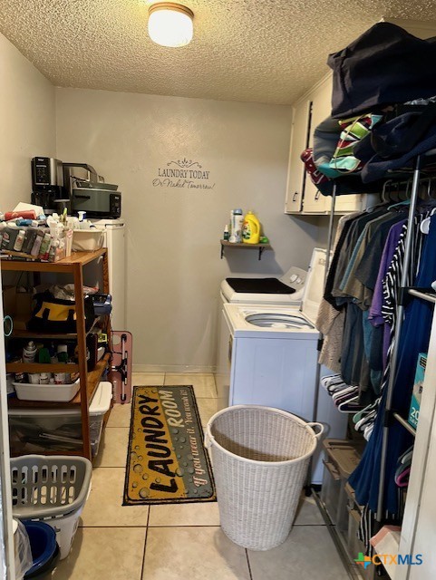 clothes washing area featuring cabinets, light tile patterned flooring, separate washer and dryer, and a textured ceiling