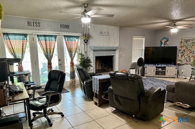 tiled living room featuring a fireplace, a textured ceiling, and ceiling fan