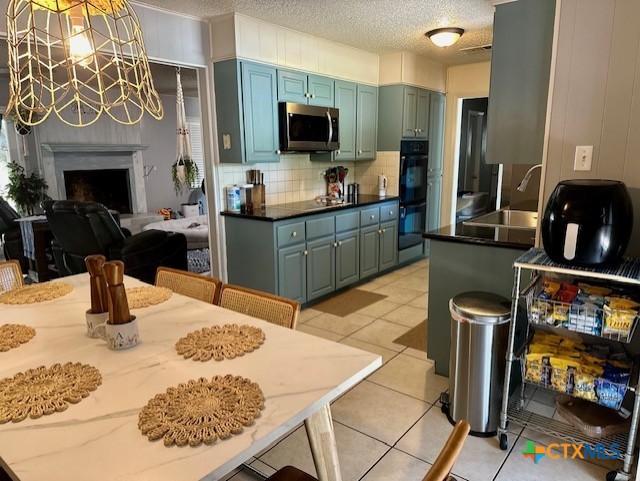 kitchen with a textured ceiling, tasteful backsplash, sink, light tile patterned flooring, and black double oven