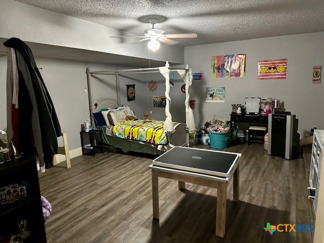 bedroom with a textured ceiling, wood-type flooring, and ceiling fan