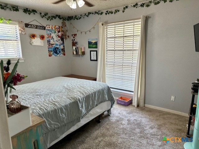 carpeted bedroom with ceiling fan and a textured ceiling