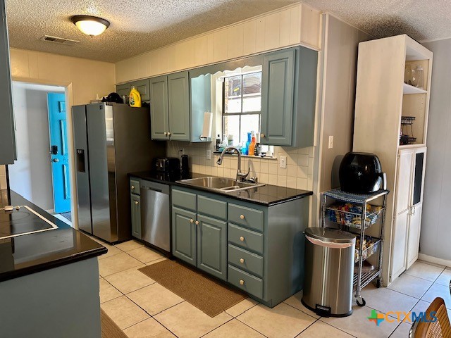 kitchen with backsplash, appliances with stainless steel finishes, sink, and light tile patterned floors