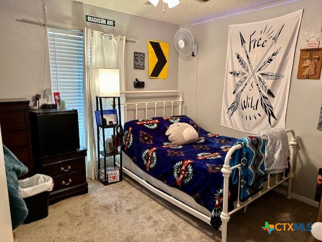 bedroom with a textured ceiling, ceiling fan, and carpet floors