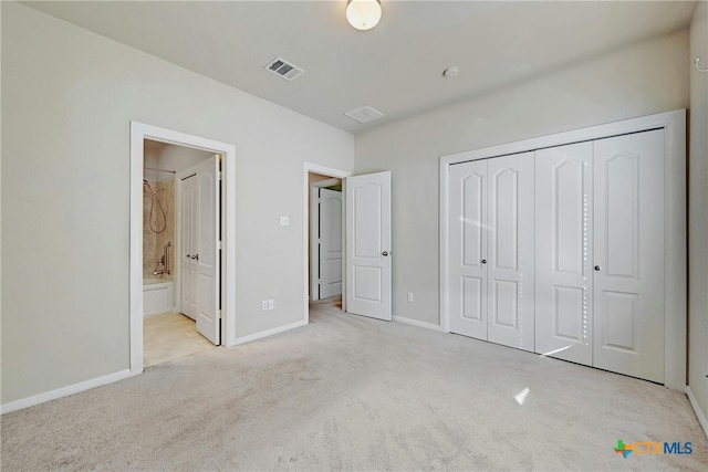 unfurnished bedroom with ensuite bathroom, light carpet, and a closet