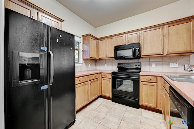 kitchen featuring light tile patterned floors, sink, black appliances, and tasteful backsplash