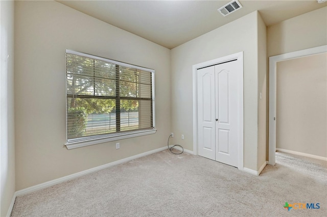 unfurnished bedroom with light colored carpet and a closet