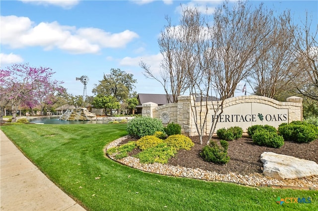 community / neighborhood sign featuring a yard and a water view