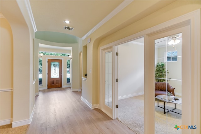 foyer entrance with ornamental molding, light wood-type flooring, and ceiling fan