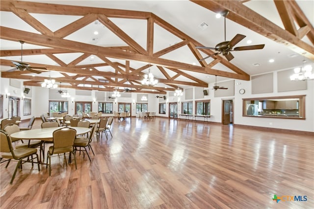 dining space with high vaulted ceiling, light hardwood / wood-style flooring, beam ceiling, and an inviting chandelier