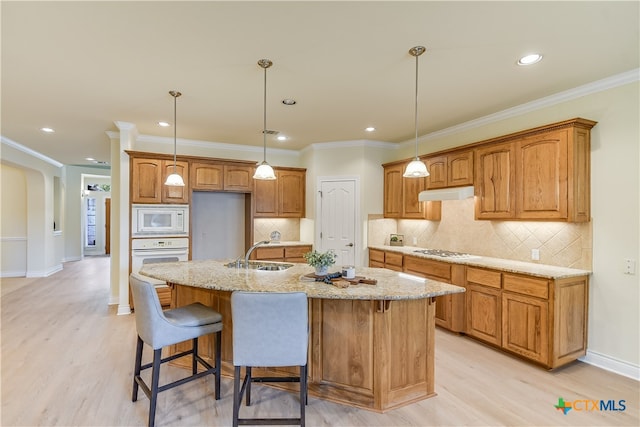 kitchen with white appliances, sink, a center island with sink, and hanging light fixtures