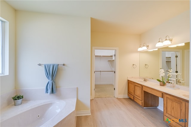 bathroom with hardwood / wood-style floors, tiled bath, and vanity