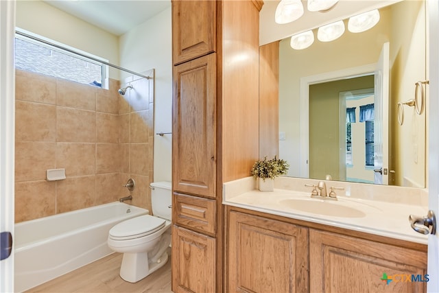 full bathroom with wood-type flooring, tiled shower / bath combo, toilet, and vanity