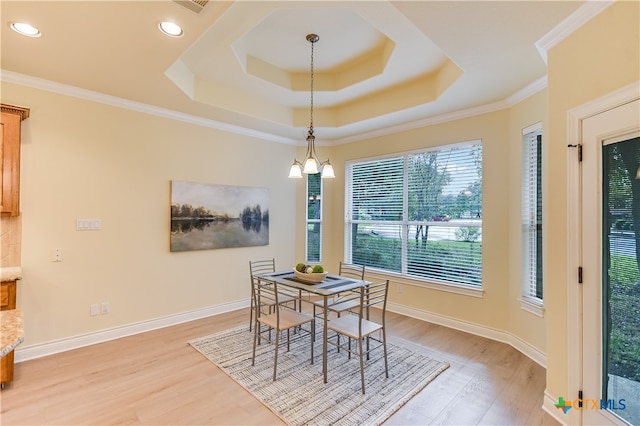 dining room with light hardwood / wood-style flooring, crown molding, a tray ceiling, and an inviting chandelier