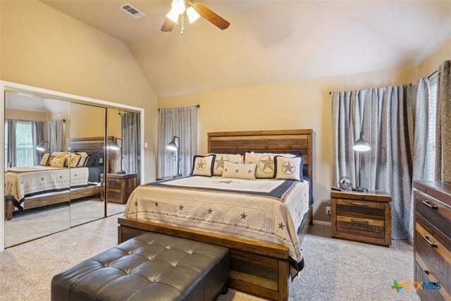 bedroom featuring a ceiling fan, light colored carpet, visible vents, vaulted ceiling, and a closet