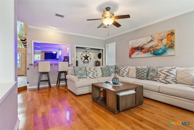living room featuring crown molding, ceiling fan, wood finished floors, and visible vents