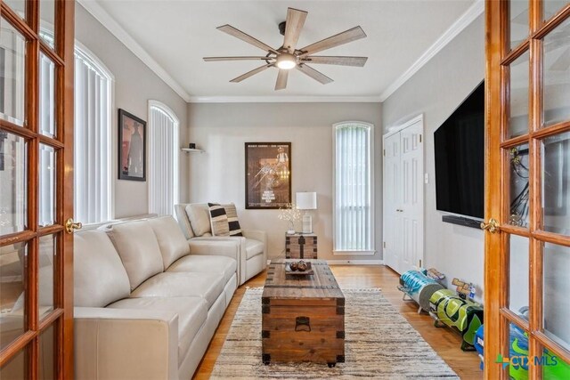 living room featuring crown molding, a ceiling fan, french doors, and light wood-type flooring