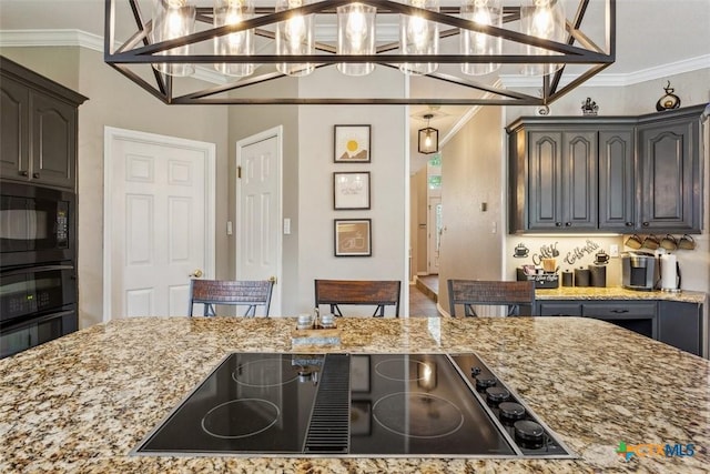 kitchen featuring crown molding, a notable chandelier, light stone counters, decorative light fixtures, and black appliances