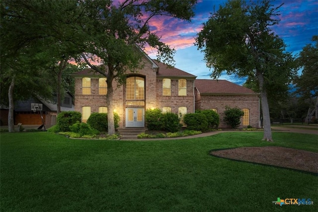 view of front of property with a lawn, french doors, and brick siding
