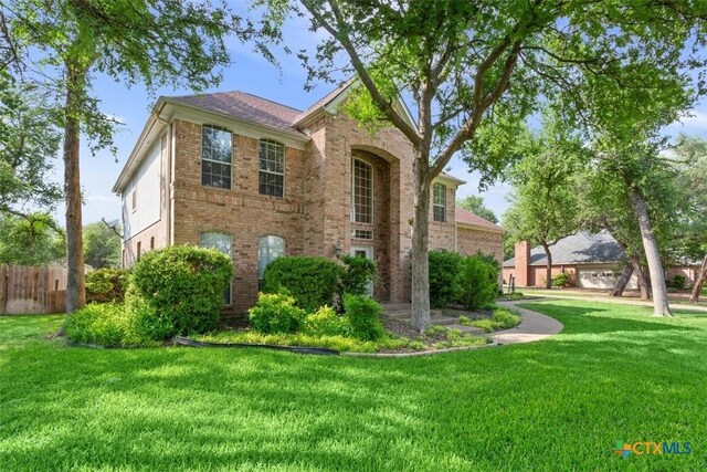 view of property exterior with a lawn, brick siding, and fence