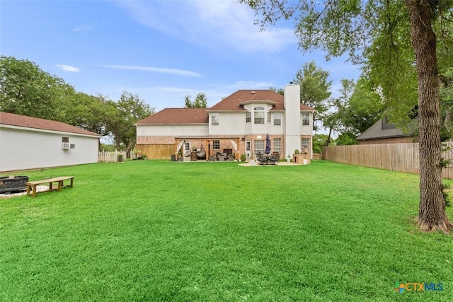 back of property with a lawn, a fenced backyard, a patio area, and a chimney