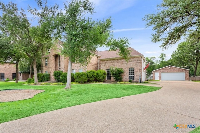 view of property hidden behind natural elements featuring brick siding, an outdoor structure, a front yard, and a garage