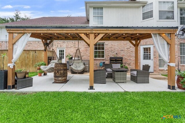 back of property with fence, a gazebo, brick siding, outdoor lounge area, and a patio