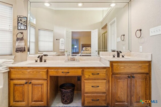 full bath with a sink, ornamental molding, and double vanity