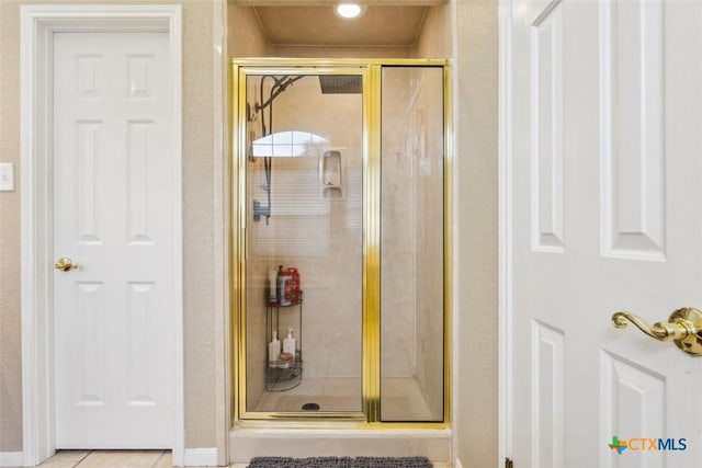 full bath with baseboards, tile patterned floors, and a stall shower