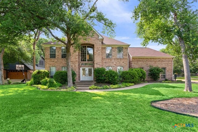 view of front facade featuring brick siding, french doors, and a front lawn