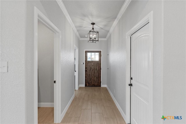 entryway featuring a textured ceiling, crown molding, and a chandelier