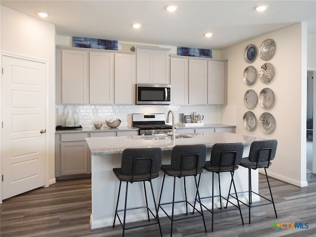 kitchen featuring a kitchen bar, dark hardwood / wood-style flooring, an island with sink, and stainless steel appliances