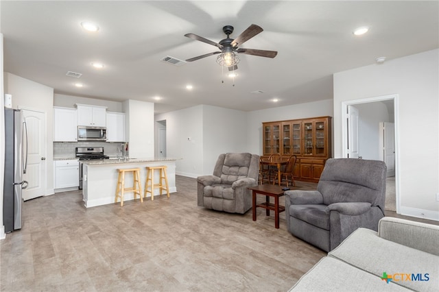 living room featuring a ceiling fan, recessed lighting, visible vents, and baseboards