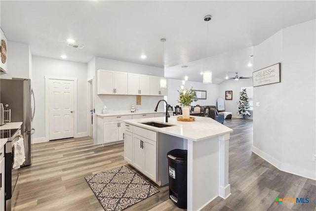 kitchen with pendant lighting, sink, white cabinetry, and a kitchen island with sink